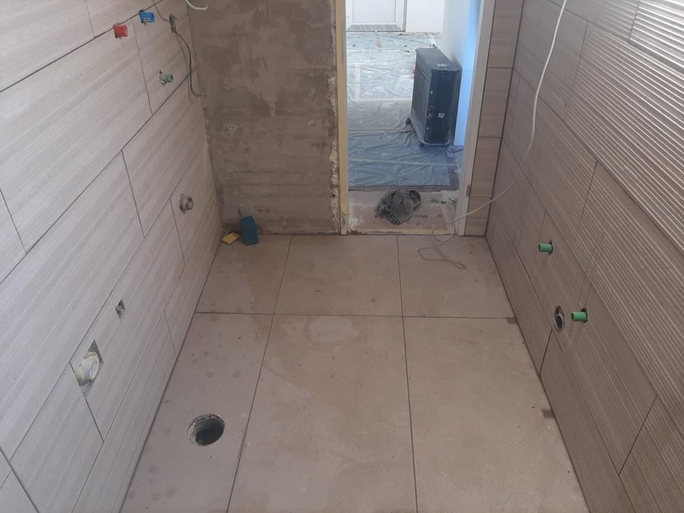 Popločana kupaonica sa zatvorenim priključcima vode i otvorom za WC odvod u podu