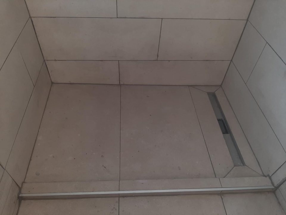 Detalj poda tuš kabine s nehrđajućim linijskim odvodom i rubnim profilom