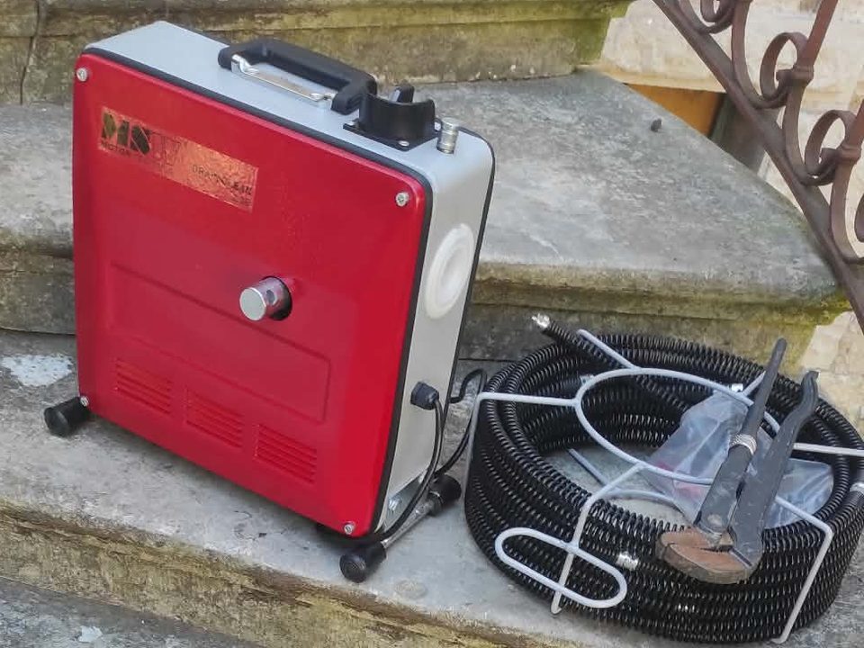 Električni stroj za odčepljenje odvoda i spiralna sajla smotana u košari, na kamenim stepenicama